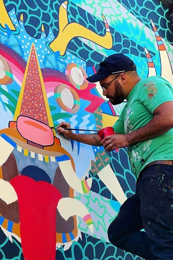 Artist Adam Hernandez Painting a Mural on a Wall